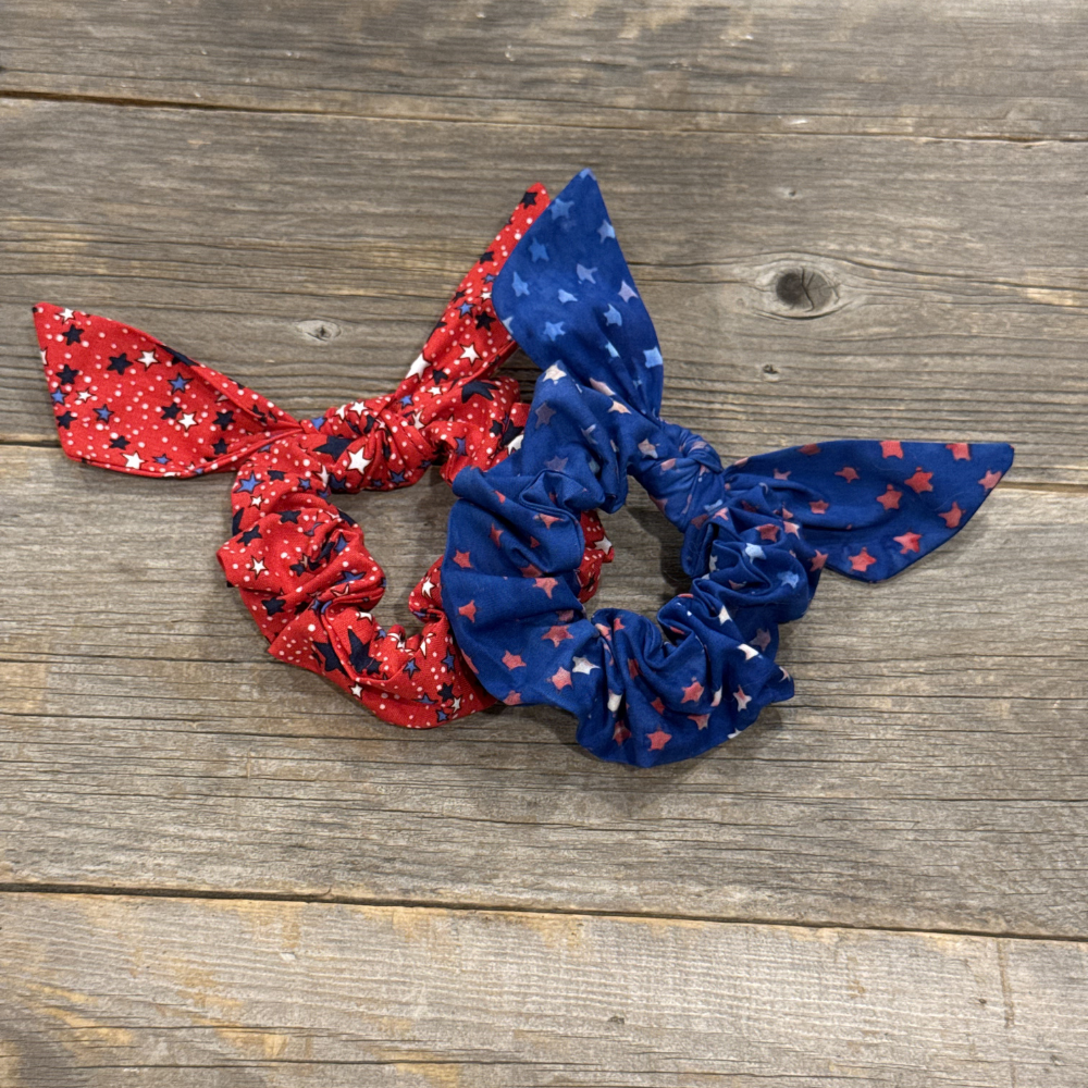 Two scrunchies, one red and one blue, with star patterns on a wooden surface.